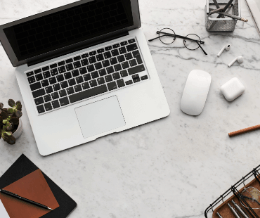 Bureau met laptop, oordopjes, muis en bril